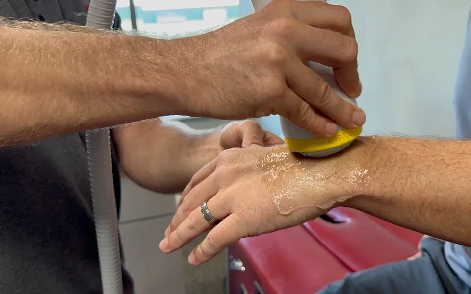 SoftWave applicator treating the back of a patient's wrist and hand